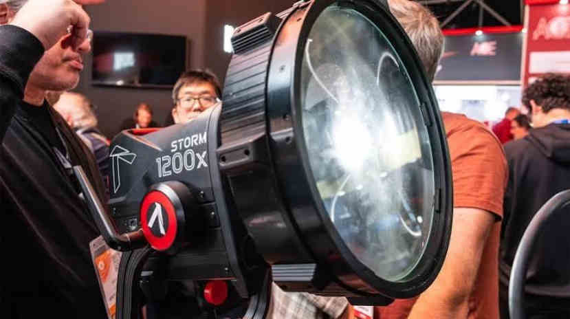 Моноблок Aputure STORM 1200x з масивною 12-дюймовою лінзою Френеля CF12 на виставковому стенді в оточенні технічних спеціалістів